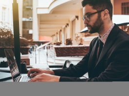 Man employer in glasses with laptop in street restaurant