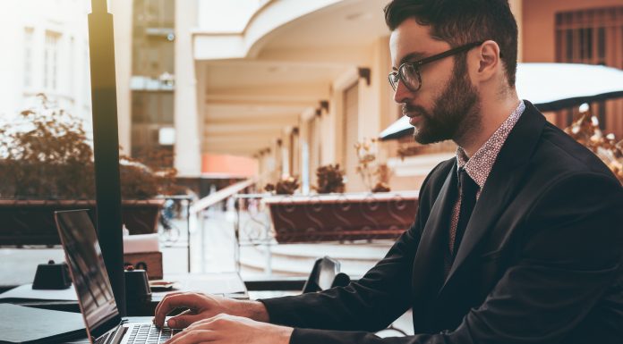 Man employer in glasses with laptop in street restaurant